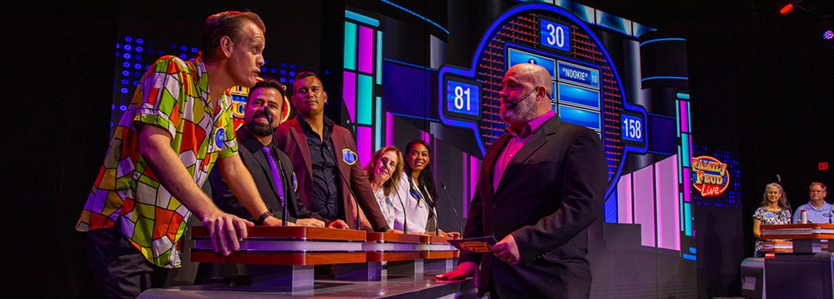 team looks on to family member about to give answer to family feud live game host
